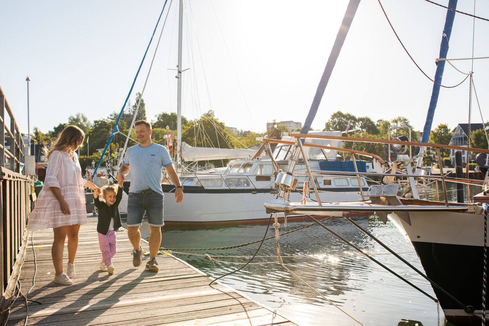 Eine Familie geht einen Steg in Heikendorf entlang. Rechts neben ihnen sind Boote zu sehen.