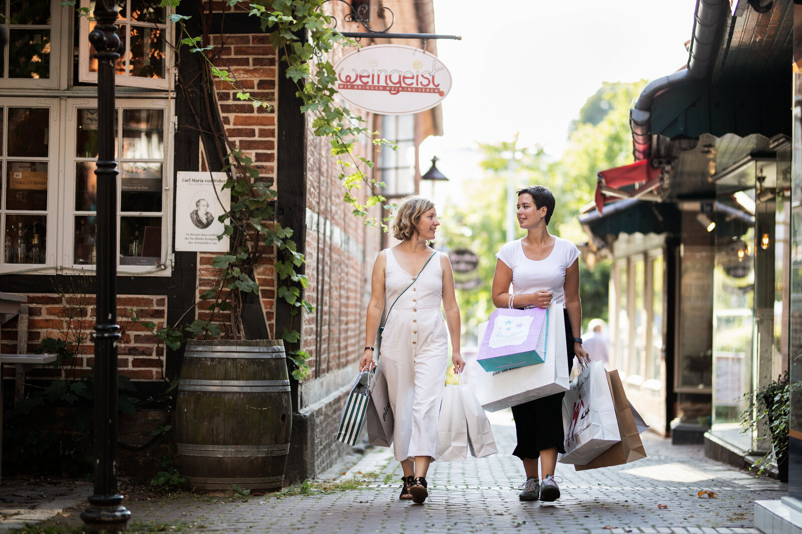 Zwei Frauen gehen mit Einkaufstaschen durch eine Gasse in Eutin.