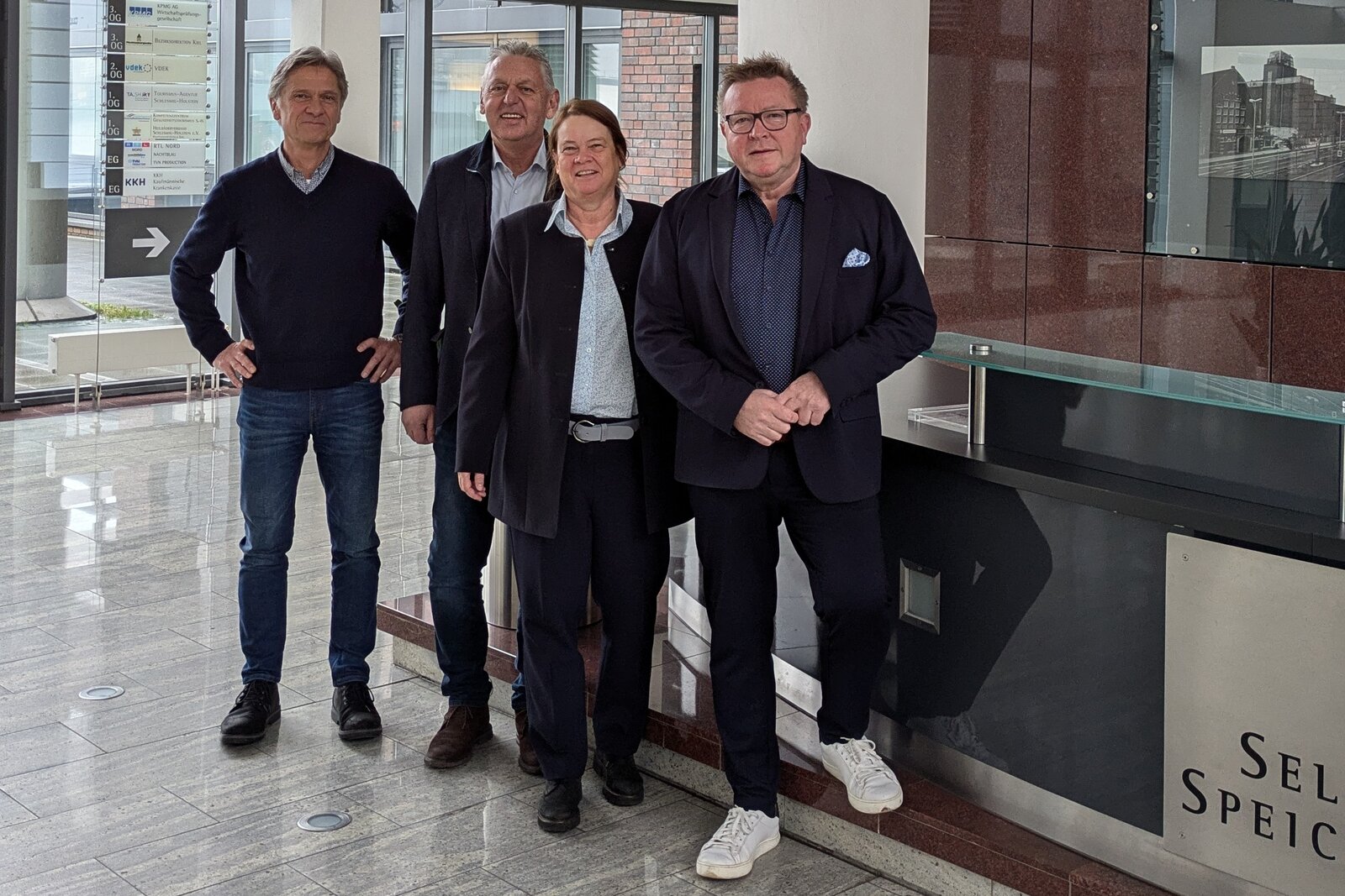 Auf dem Bild sind von links nach rechts Peter Douven, Manfred Wohnrade, Dr. Catrin Homp und Hans-Jürgen Lütje in einem Foyer zu sehen.