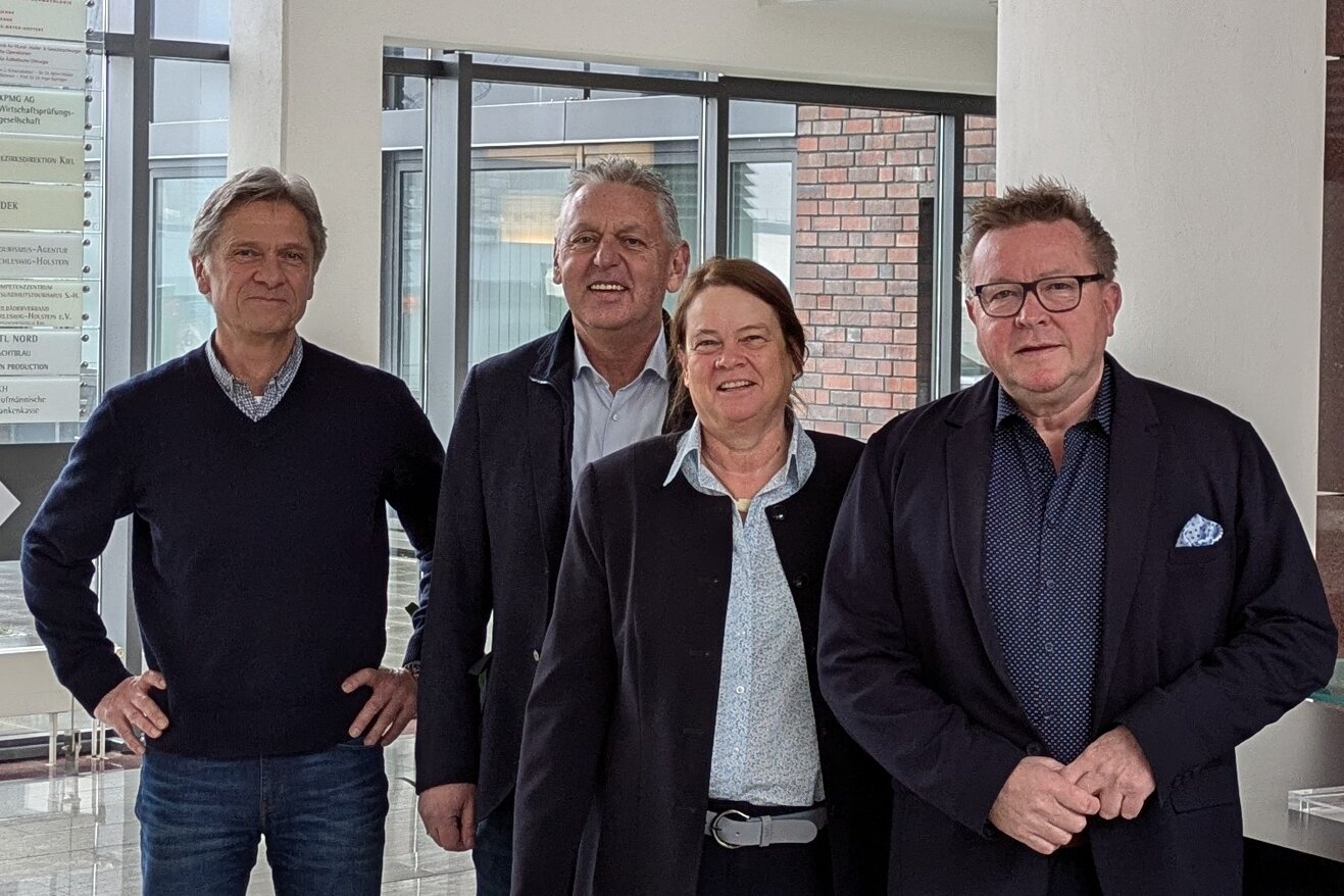 Auf dem Bild sind von links nach rechts Peter Douven, Manfred Wohnrade, Dr. Catrin Homp und Hans-Jürgen Lütje in einem Foyer zu sehen.